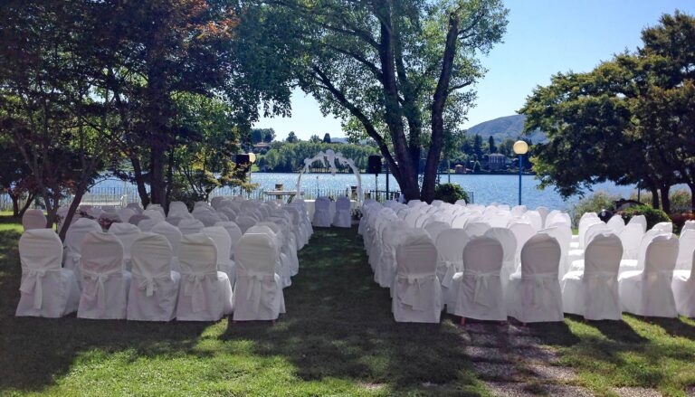 Rows of white-covered chairs under the trees at Hotel L'Approdo, Lake Orta, set for a ceremony by the water, Italian Wedding Company
