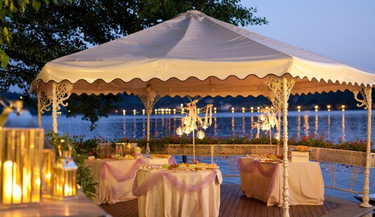 A lakeside pavilion at Hotel L'Approdo, Lake Orta, at dusk, candles and lanterns around the dressed tables, Italian Wedding Company