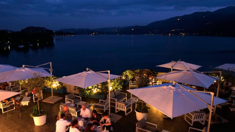 The lakeside terrace at Hotel Giardinetto at blue hour, parasols lit and guests at dinner above Lake Orta, Italian Wedding Company
