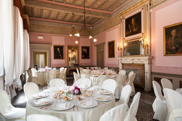 A frescoed salon at Palazzo Penotti Ubertini, Lake Orta, laid for a wedding dinner beneath family portraits, Italian Wedding Company