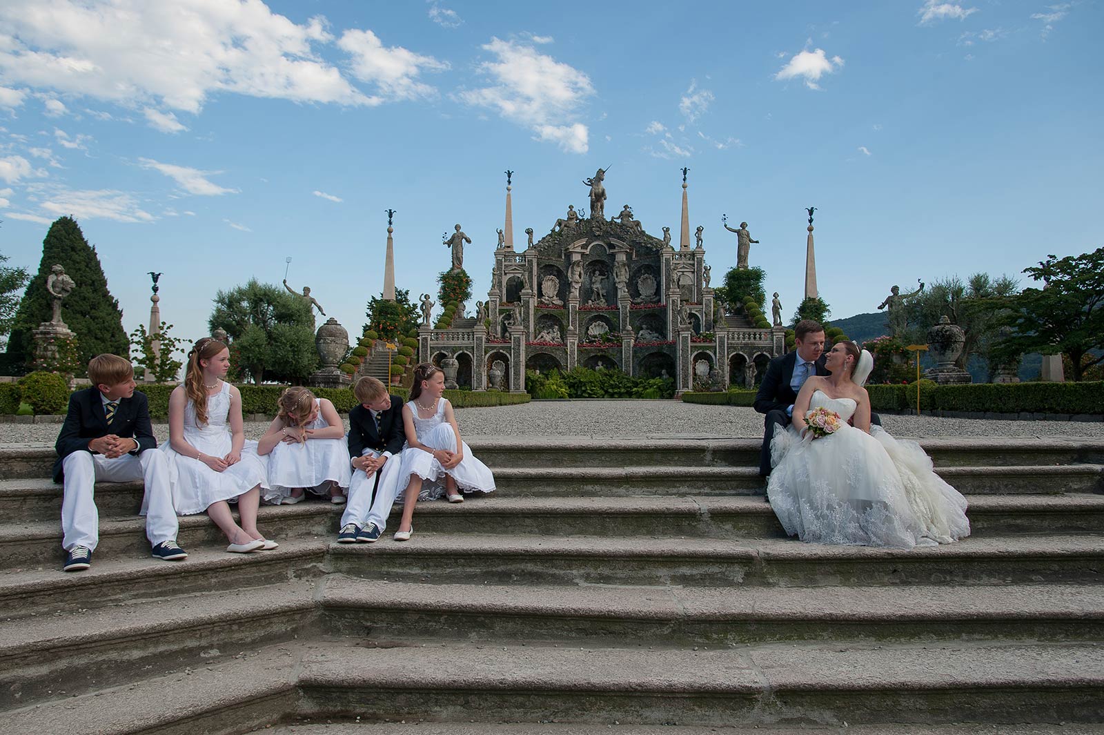 The wedding party seated on the stone steps of the baroque garden on Isola Bella, Lake Maggiore, Italian Wedding Company