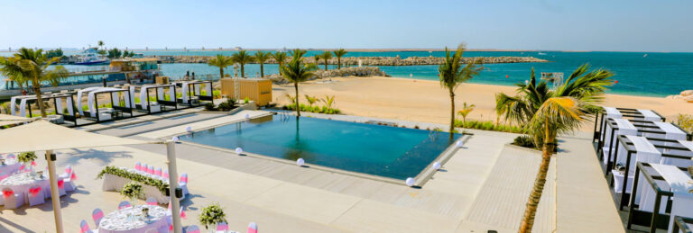 Soul Beach, the beachfront event space, set with banquet tables beside the pool, Jebel Ali Golf Resort