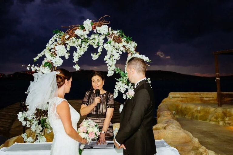 An evening ceremony beneath a white blossom arch by the sea, Jewelweddings Event Planners
