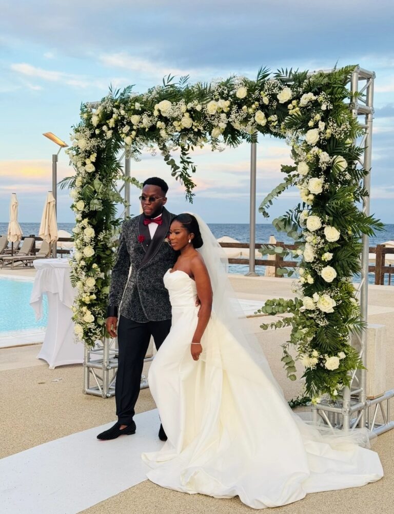 A couple before a floral arch beside the pool, sea beyond, Jewelweddings Event Planners
