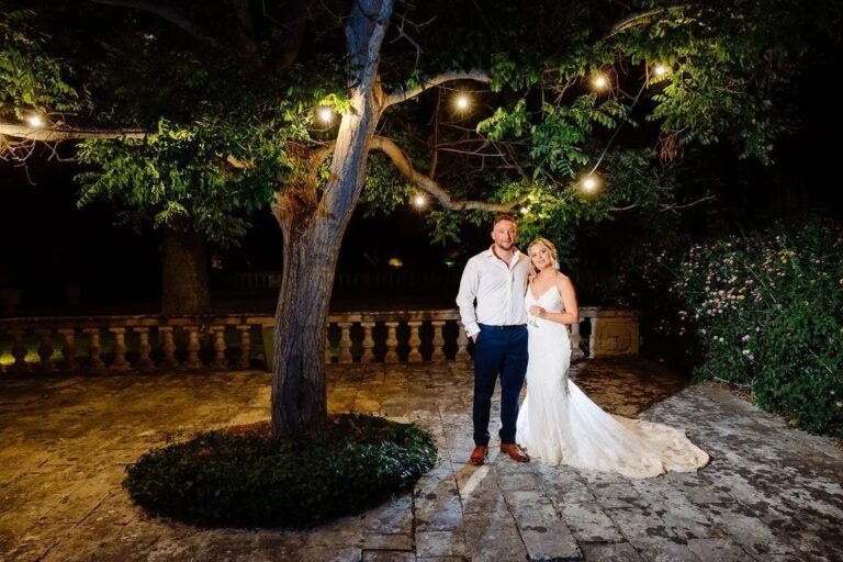 The couple standing together in a garden lit with string lights at night, Jewelweddings Event Planners
