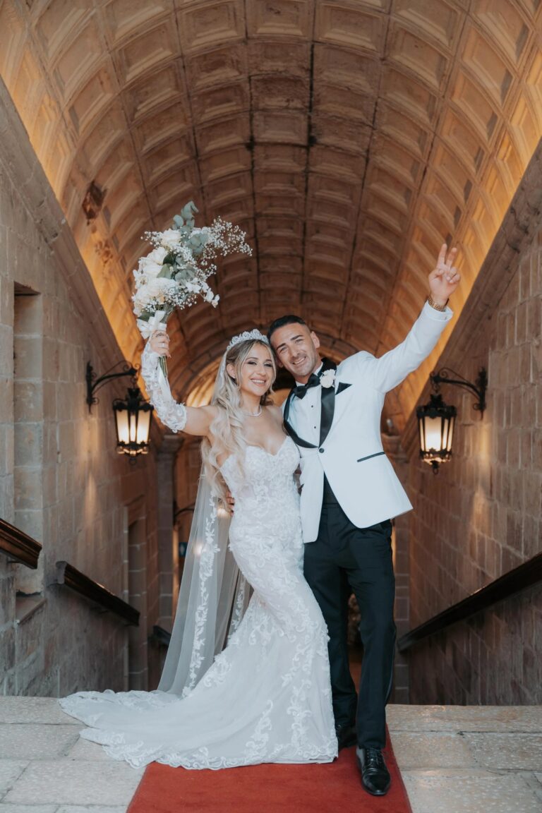 The couple cheering in a stone arcade, Malta, Jewelweddings Event Planners