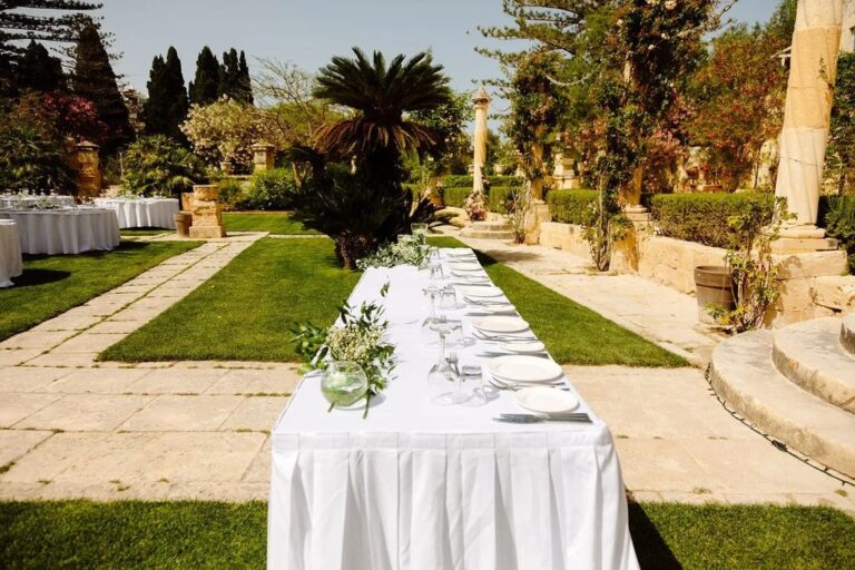A long banquet table laid between clipped lawns, Jewelweddings Event Planners