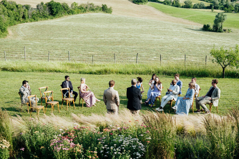 A small ceremony in a circle of chairs on the meadow at Palazzo Serre, San Leo, in the Romagna hills, Joy Wedding