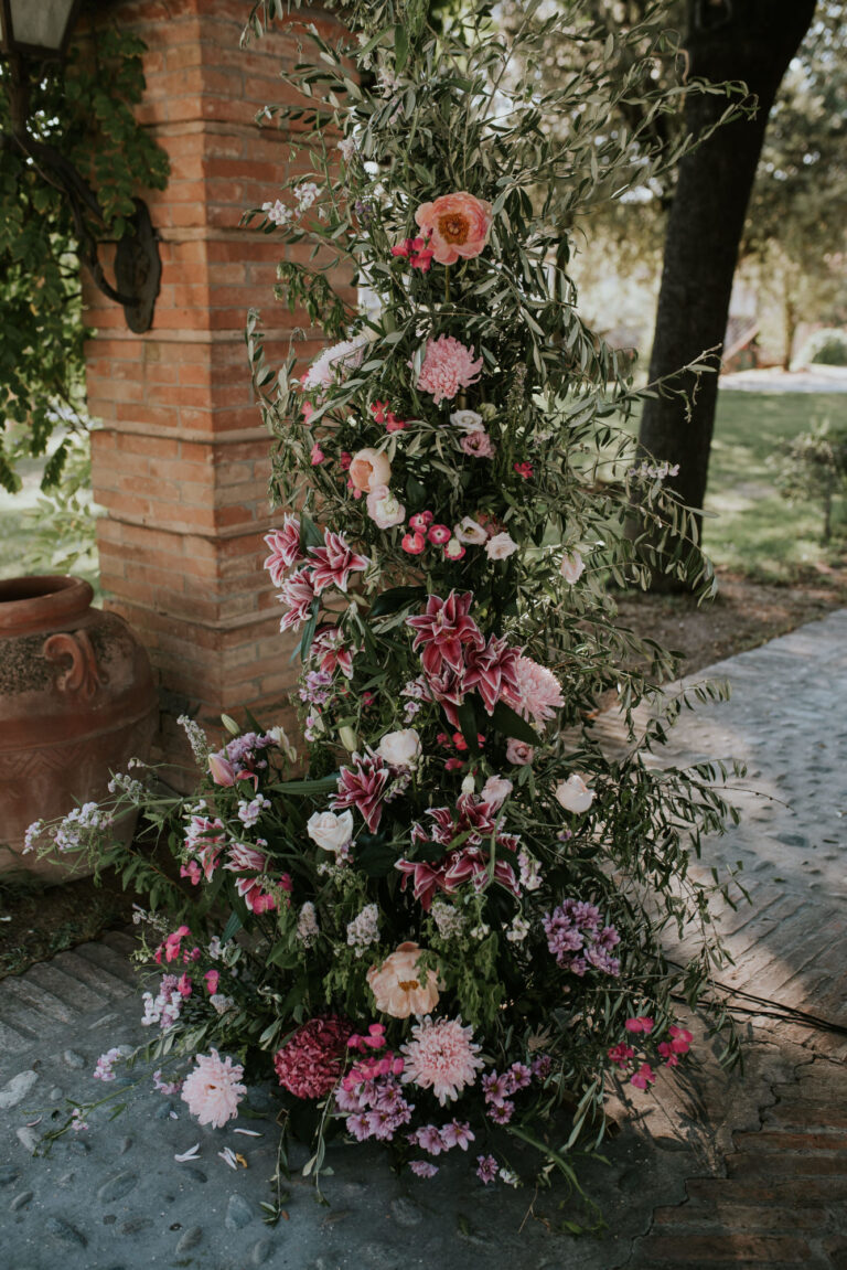 A column of pink and coral flowers beside a brick pillar at Tenuta del Tempio Antico, Rimini, Joy Wedding