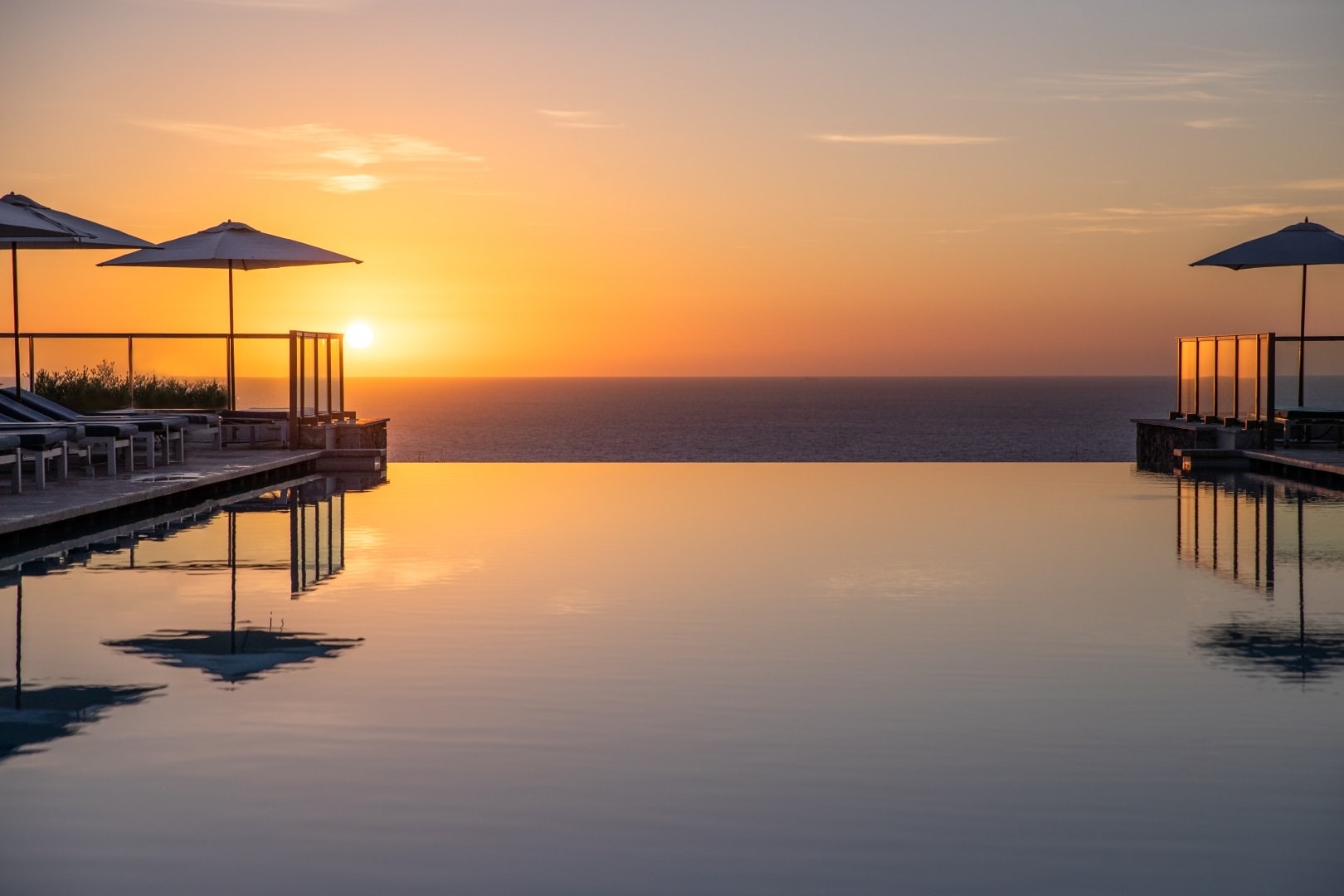 The infinity pool at sunset, the Mediterranean turning gold beyond the clifftop and the umbrellas mirrored in still water, Jumeirah Port Soller Hotel & Spa