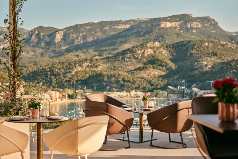 A terrace laid for dinner at golden hour, the port and the Tramuntana mountains beyond, Jumeirah Port Soller Hotel & Spa