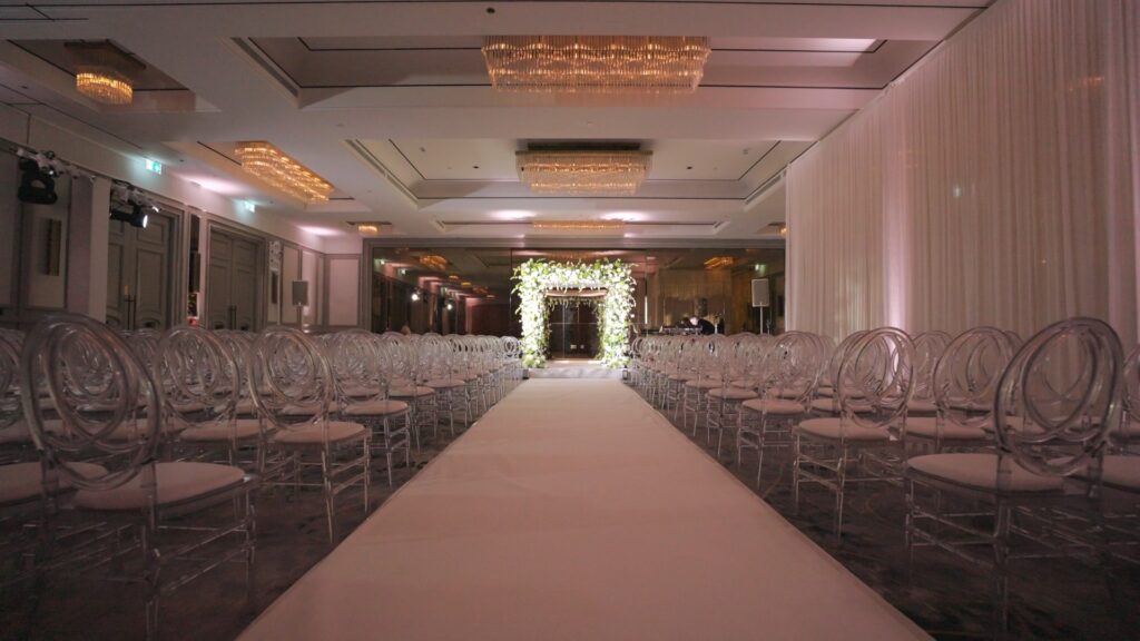 Floral chuppah at the end of a white aisle in a hotel ballroom, Just Smile Ltd