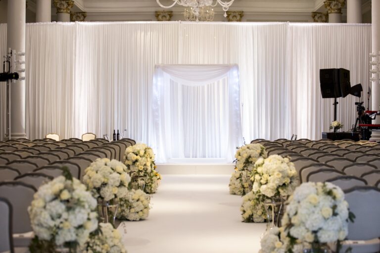 White draped chuppah with hydrangeas along a white aisle, Just Smile Ltd