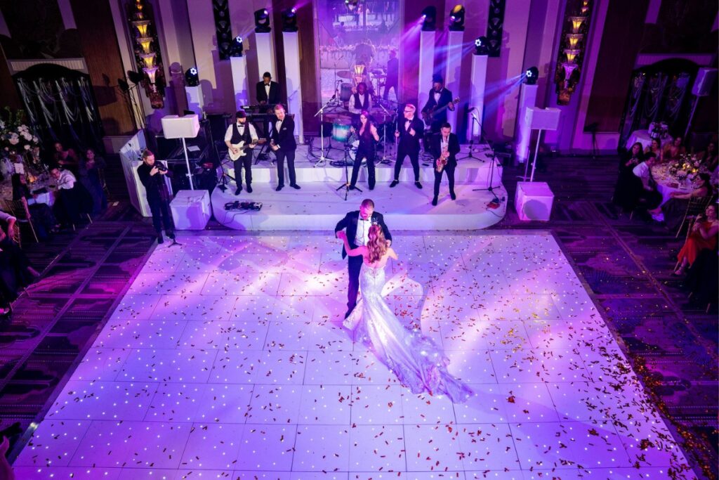 The first dance on a lit white dance floor with the band on stage behind