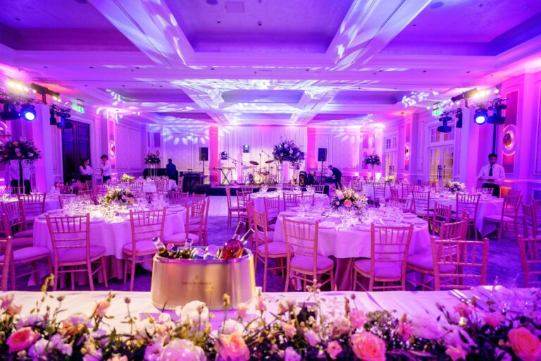 Ballroom reception in magenta uplighting with a floral sweetheart table, Just Smile Ltd