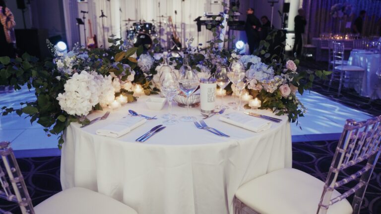 Round table with a white floral centrepiece under blue and white lighting, Just Smile Ltd