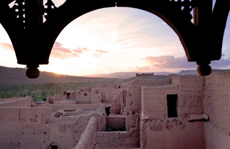Sunset over the kasbah roofs seen through a carved wooden arch, Kasbah des Caïds