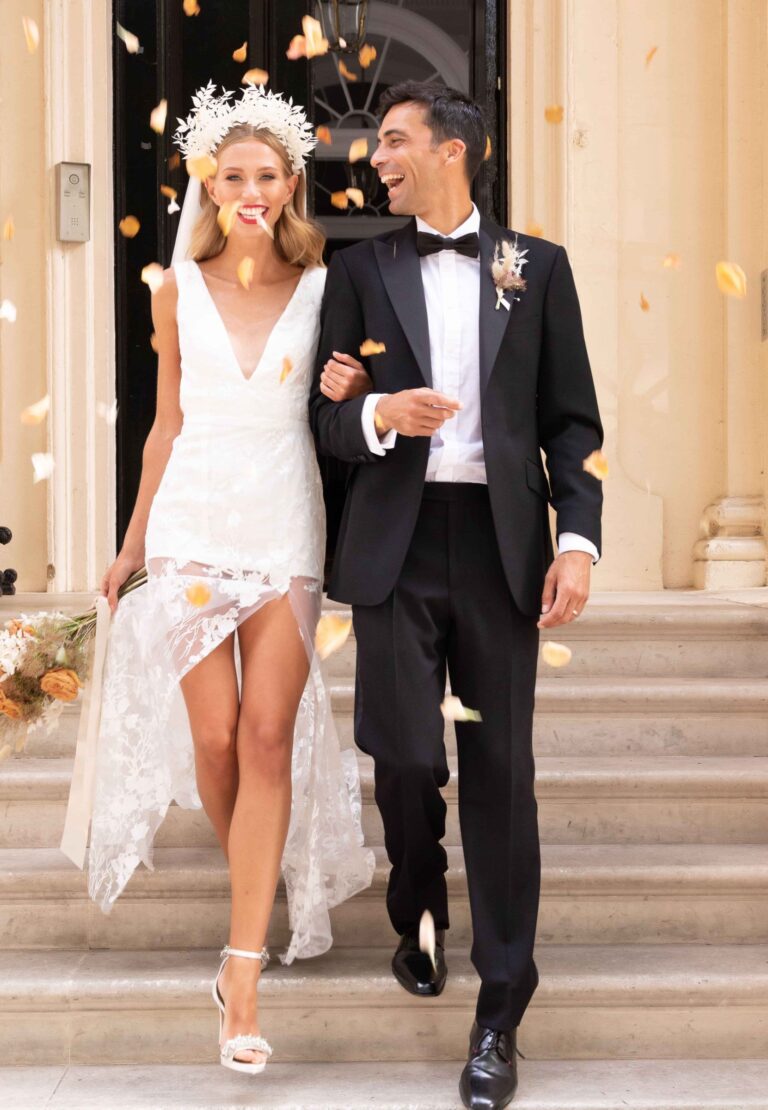 A bride in a lace hem dress and veil walking down stone steps with her groom, Kate Edmondson Bridal Couture