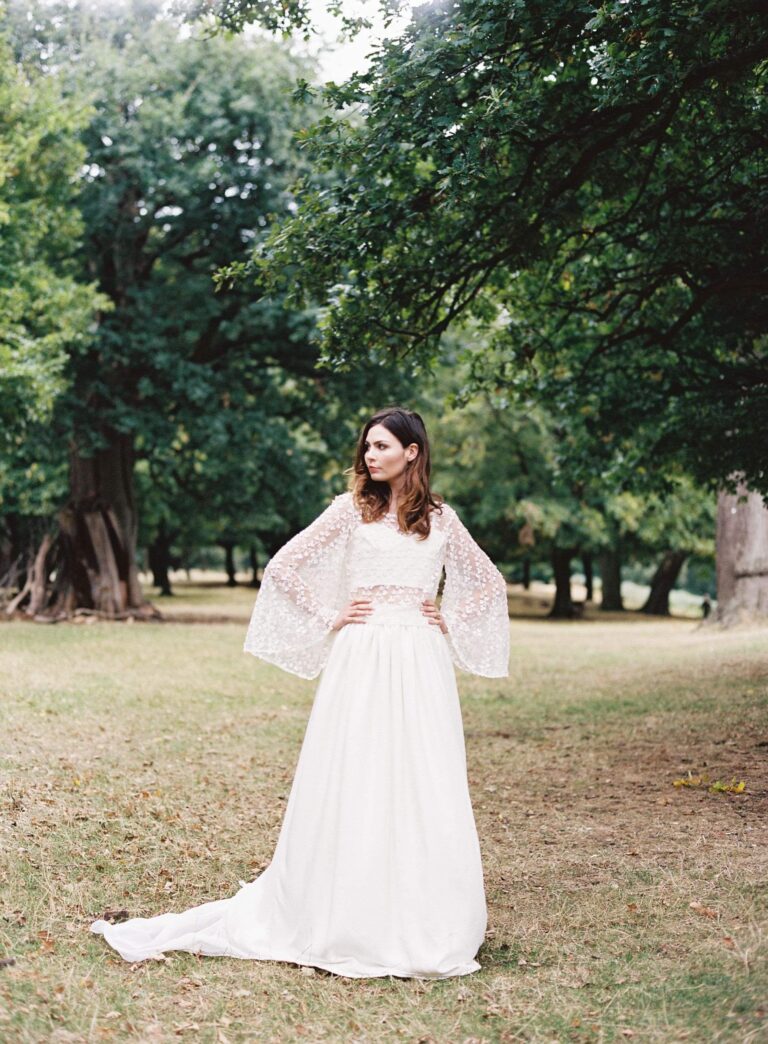 A gown with flared sleeves and a long skirt in open parkland, Kate Edmondson Bridal Couture