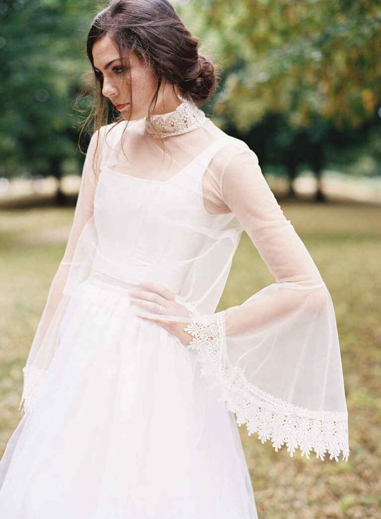 A gown with sheer bell sleeves and lace trim in parkland, Kate Edmondson Bridal Couture