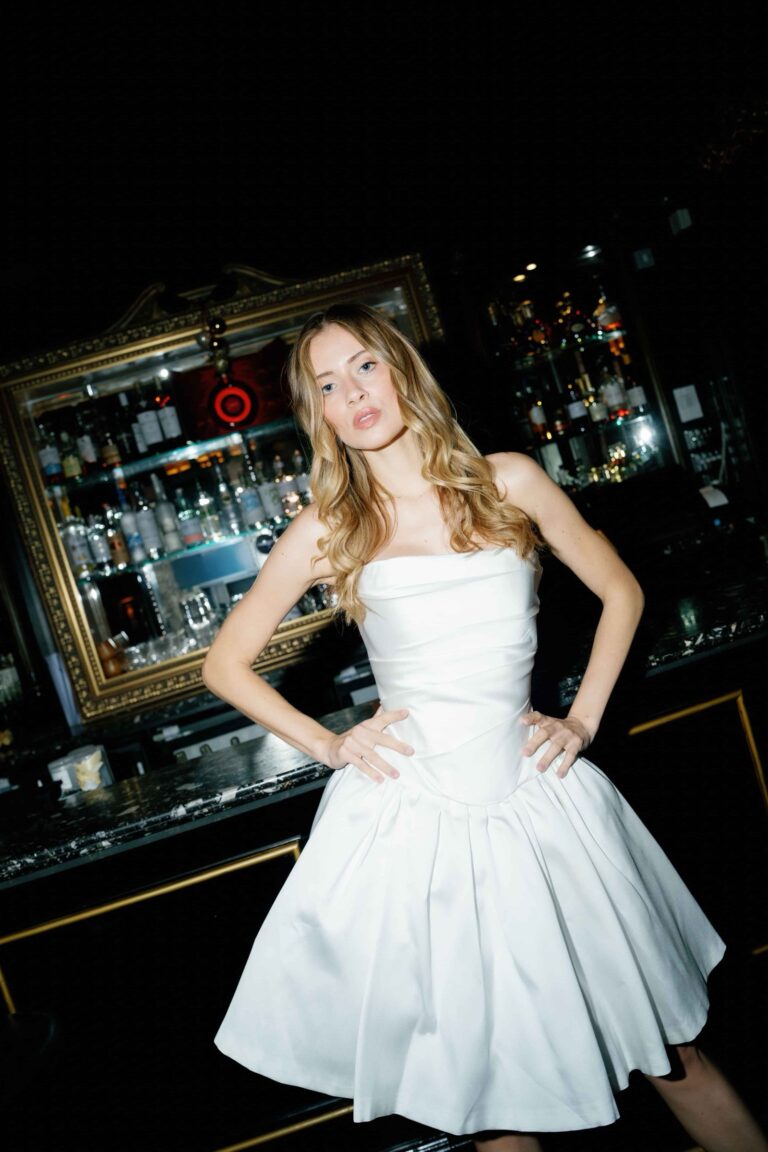 A strapless full skirted satin dress in a dark panelled bar, Kate Edmondson Bridal Couture