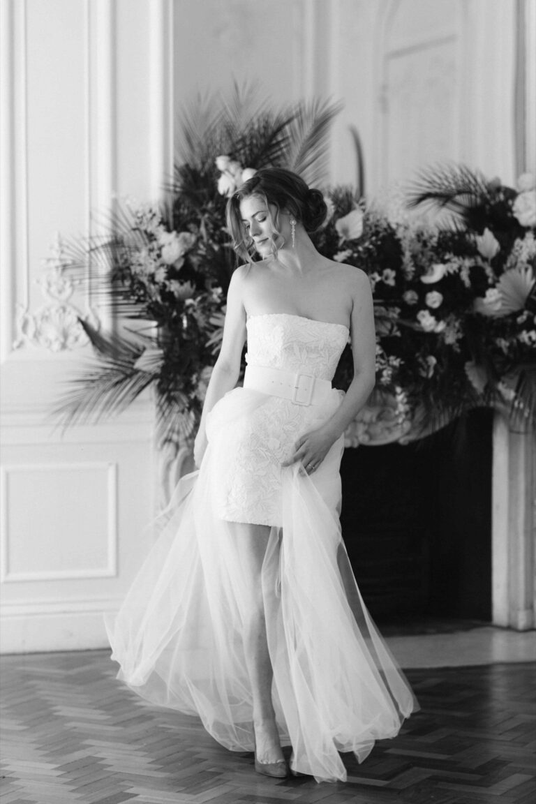 A strapless dress with a tulle skirt in front of dark foliage, in black and white, Kate Edmondson Bridal Couture