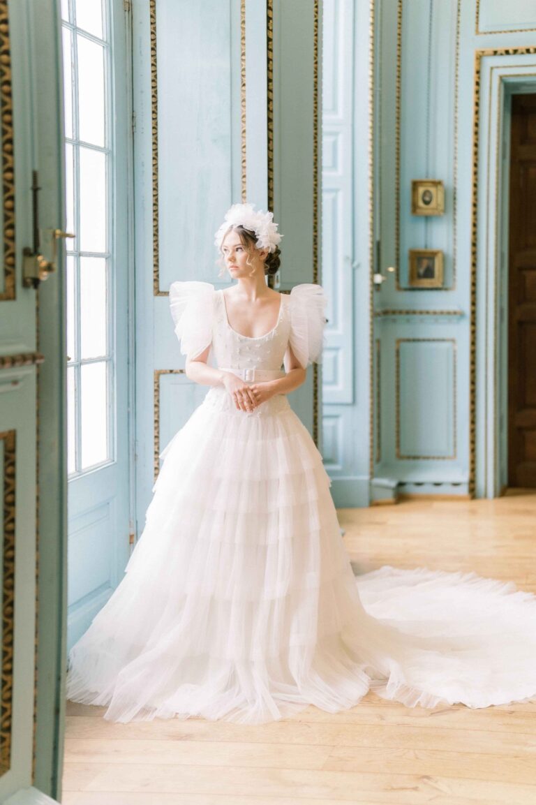 A tiered gown with puffed shoulders in a pale blue salon, Kate Edmondson Bridal Couture