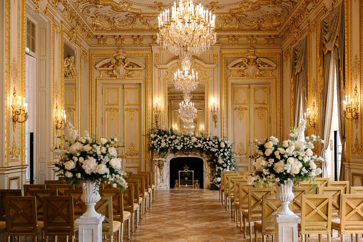 A ceremony aisle lined with chairs and white flowers in a gilded salon at Shangri-La Paris
