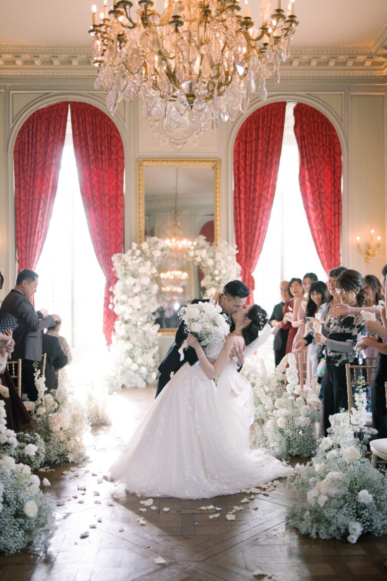 Couple at a floral arch before red curtains in a Parisian salon, Katerina Meyvial Wedding & Event Planner