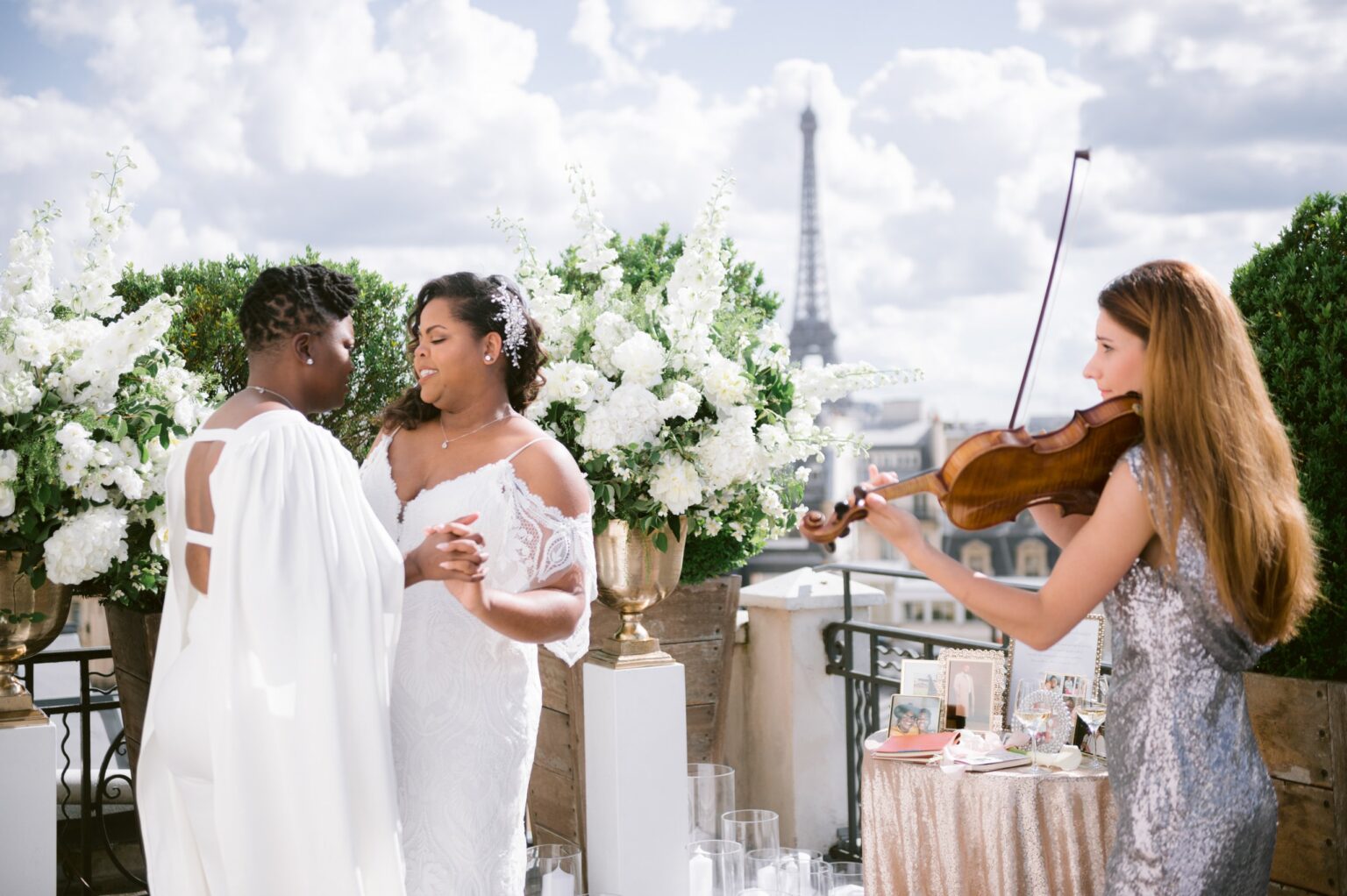 A rooftop ceremony with a violinist and a white flower arch, the Eiffel Tower behind