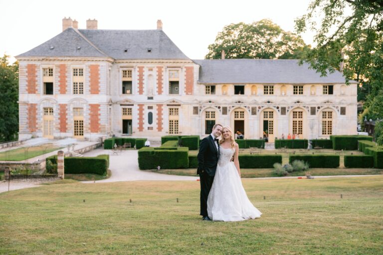 Couple on the lawn in front of a brick and stone château, Katerina Meyvial Wedding & Event Planner