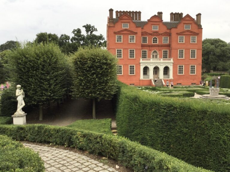 The palace framed by clipped yew hedges and topiary in the Queen's Garden, a marble figure at the path, Kew Palace