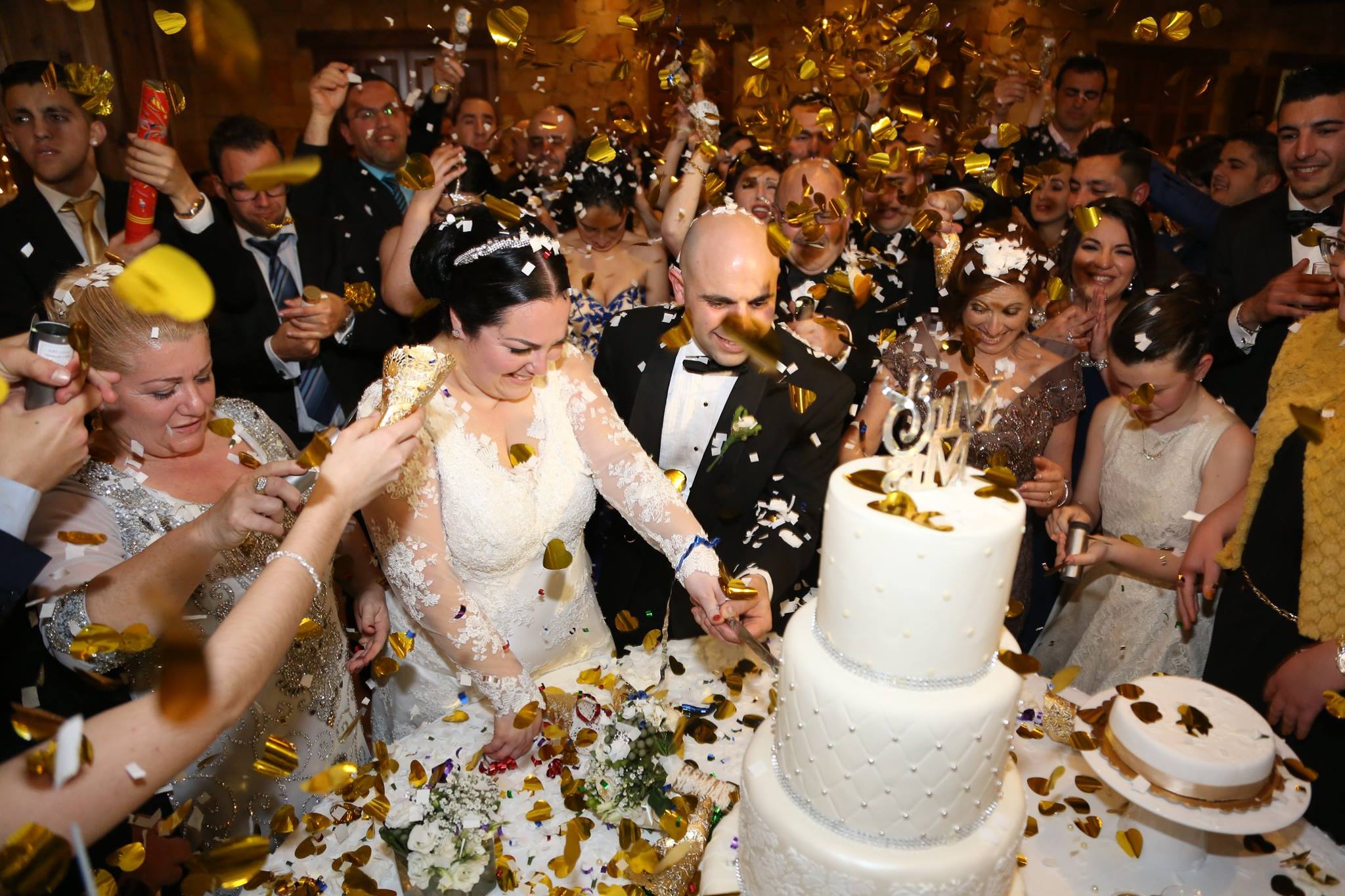 Cutting the wedding cake as guests throw confetti, KG Events Malta