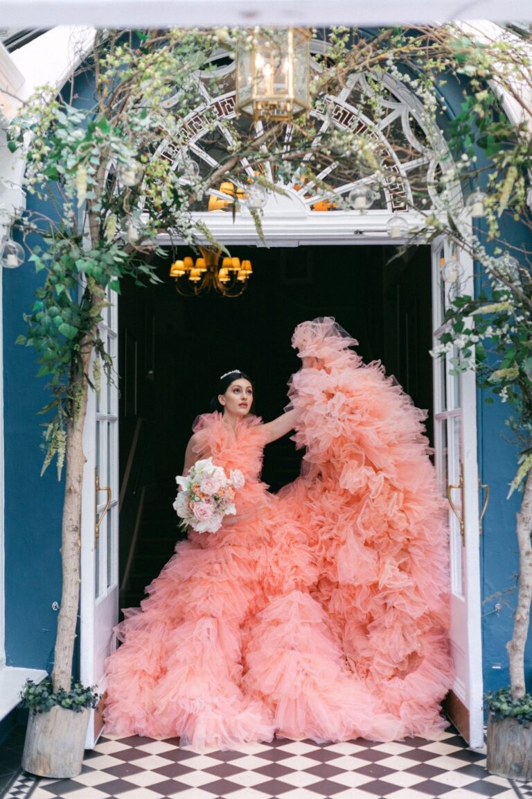 A blush ruffled gown, beneath a white floral archway, Khushi The Makeup Artist
