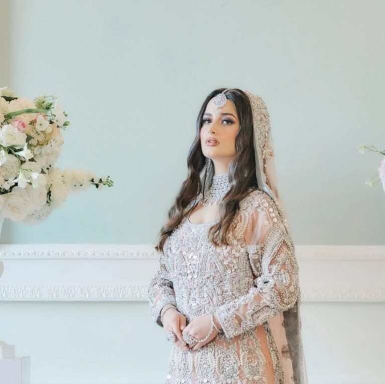 An ivory bridal gown, dupatta veil, white roses behind, Khushi The Makeup Artist