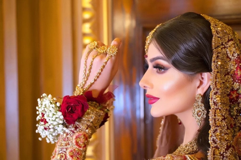 A red bridal look in profile, floral hair accessory, Khushi The Makeup Artist