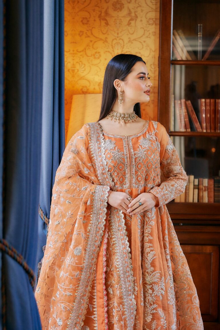 A peach lehenga and layered pearl necklaces, library shelves behind, Khushi The Makeup Artist