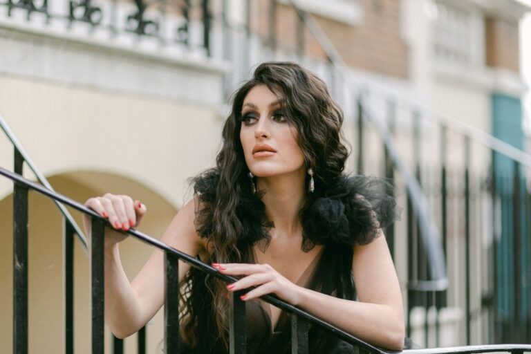 A black feather-trimmed gown against a blue doorway, Khushi The Makeup Artist