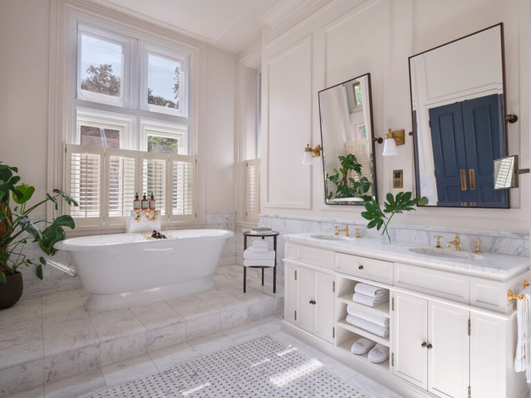 A suite bathroom with a freestanding bath under shuttered windows and a marble double vanity, Kimpton Fitzroy London