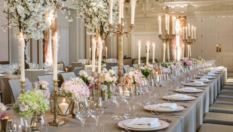 A long table dressed with tall gold candlesticks, white blossom and mixed pastel flowers, Kimpton Fitzroy London