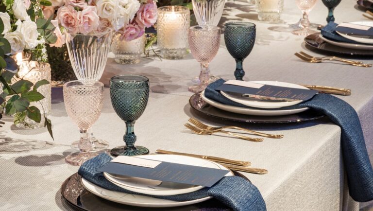 A place setting with blue glassware, navy napkins and pink roses on grey linen, Kimpton Fitzroy London