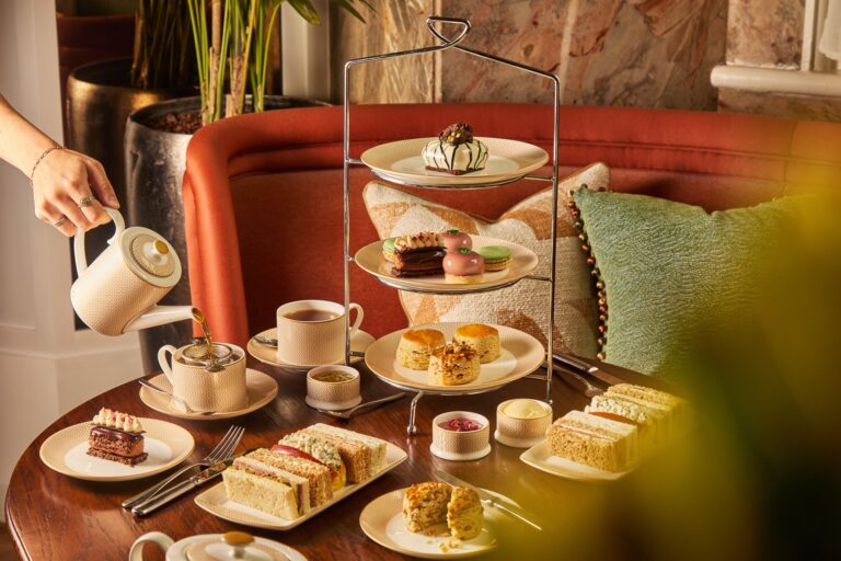 Afternoon tea on a tiered stand, with tea being poured at a banquette table, Kimpton Fitzroy London