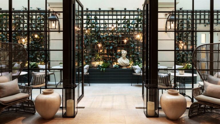 The indoor winter garden off Palm Court, with trellis walls, a stone bust and wicker chairs, Kimpton Fitzroy London