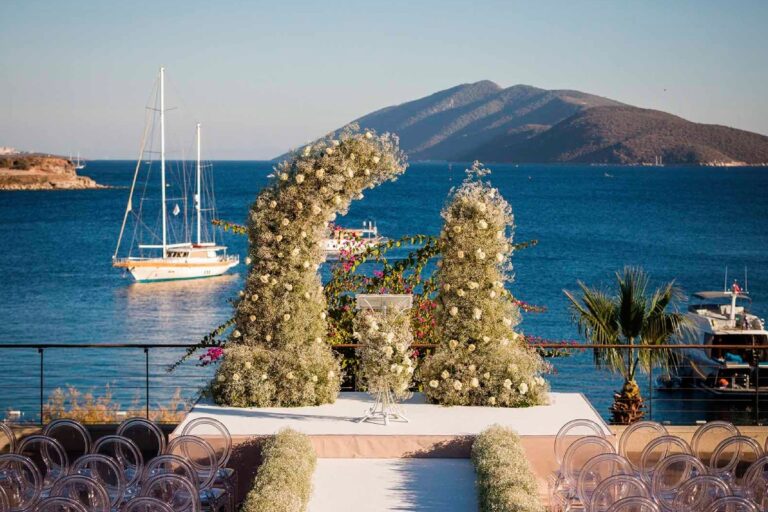 A coastal wedding arrangement with a boat on the water behind, KM Events