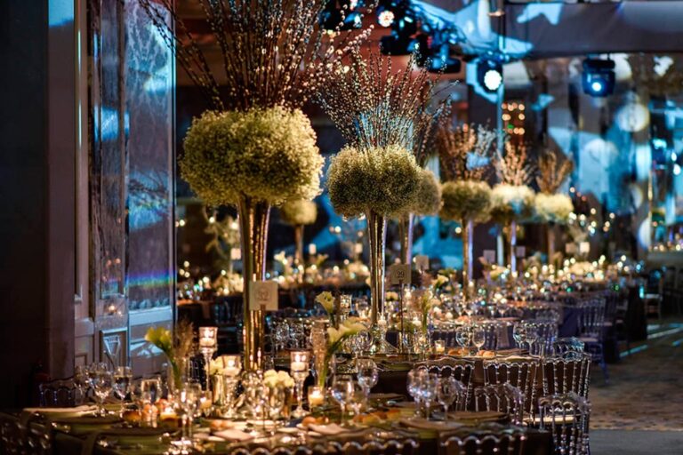 A banquet with tall flower centrepieces under stage lighting, KM Events