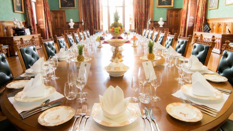 A long dining table laid in a panelled room, Knowsley Hall