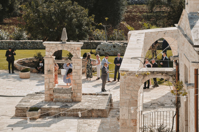 The stone courtyard of a Puglian masseria with a well and arches, La Bottega del Sogno