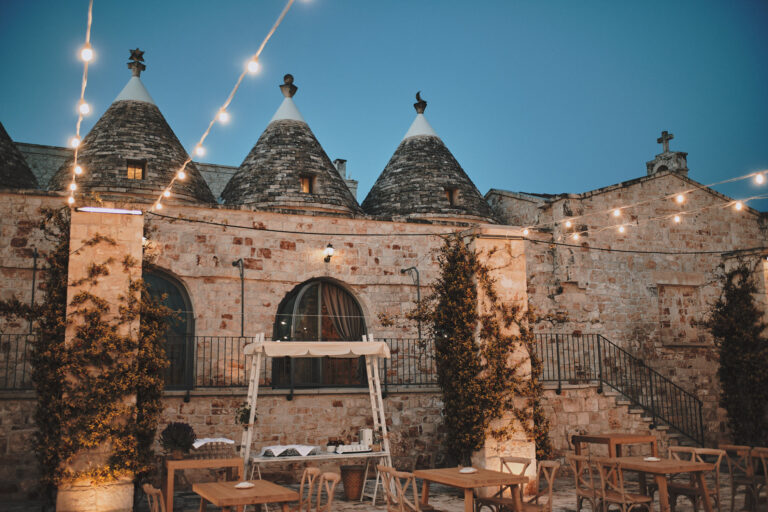 Trulli roofs at dusk strung with lights above the dinner tables, Puglia, La Bottega del Sogno