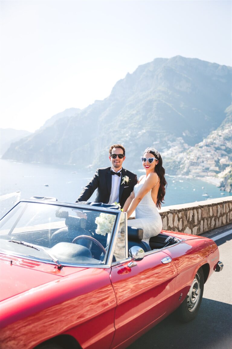 The couple in a red vintage Alfa Romeo convertible on the coast road above Positano, La Calla Events