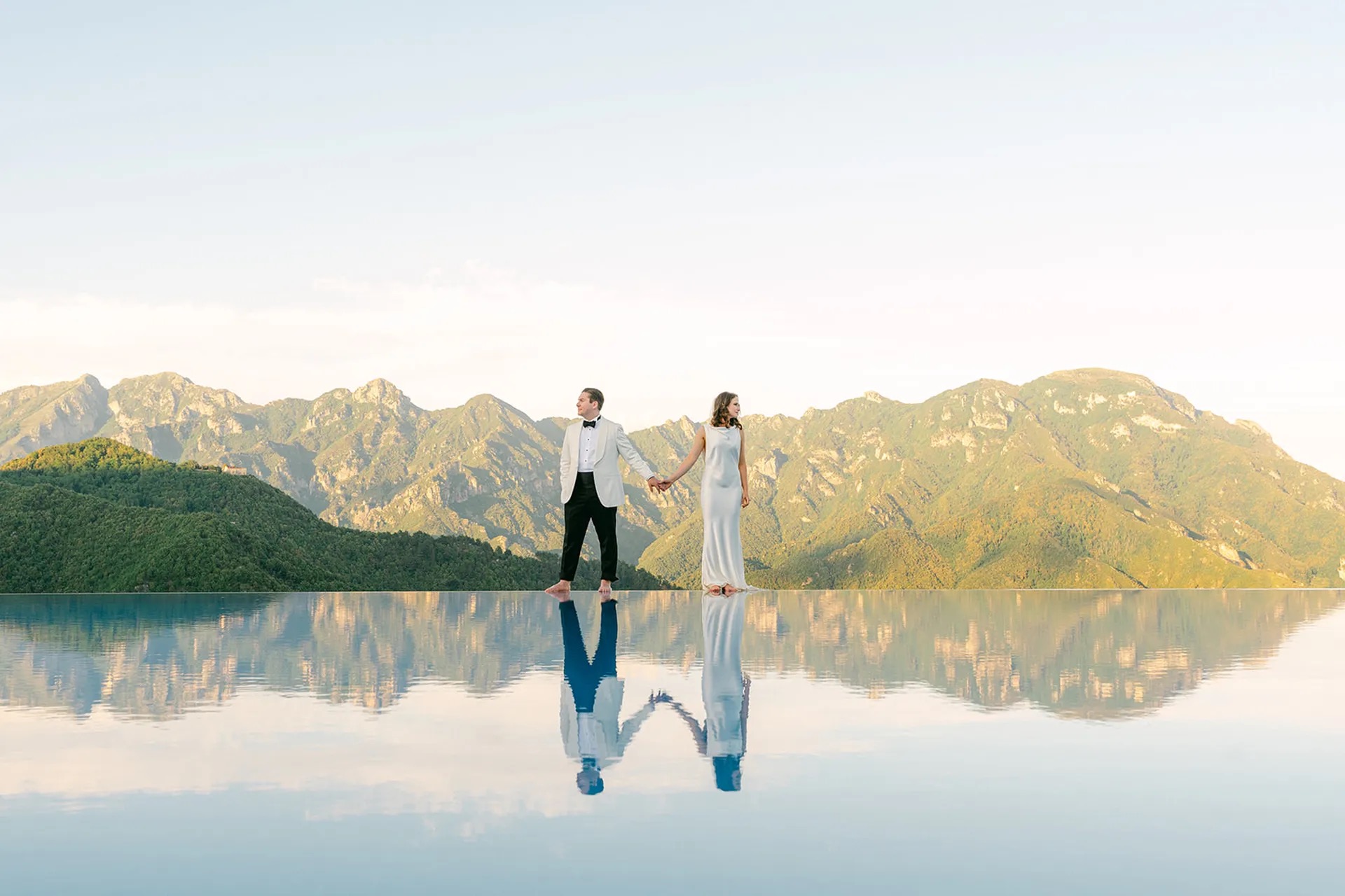 A couple reflected in an infinity pool against the mountains of the Amalfi Coast, La Calla Events